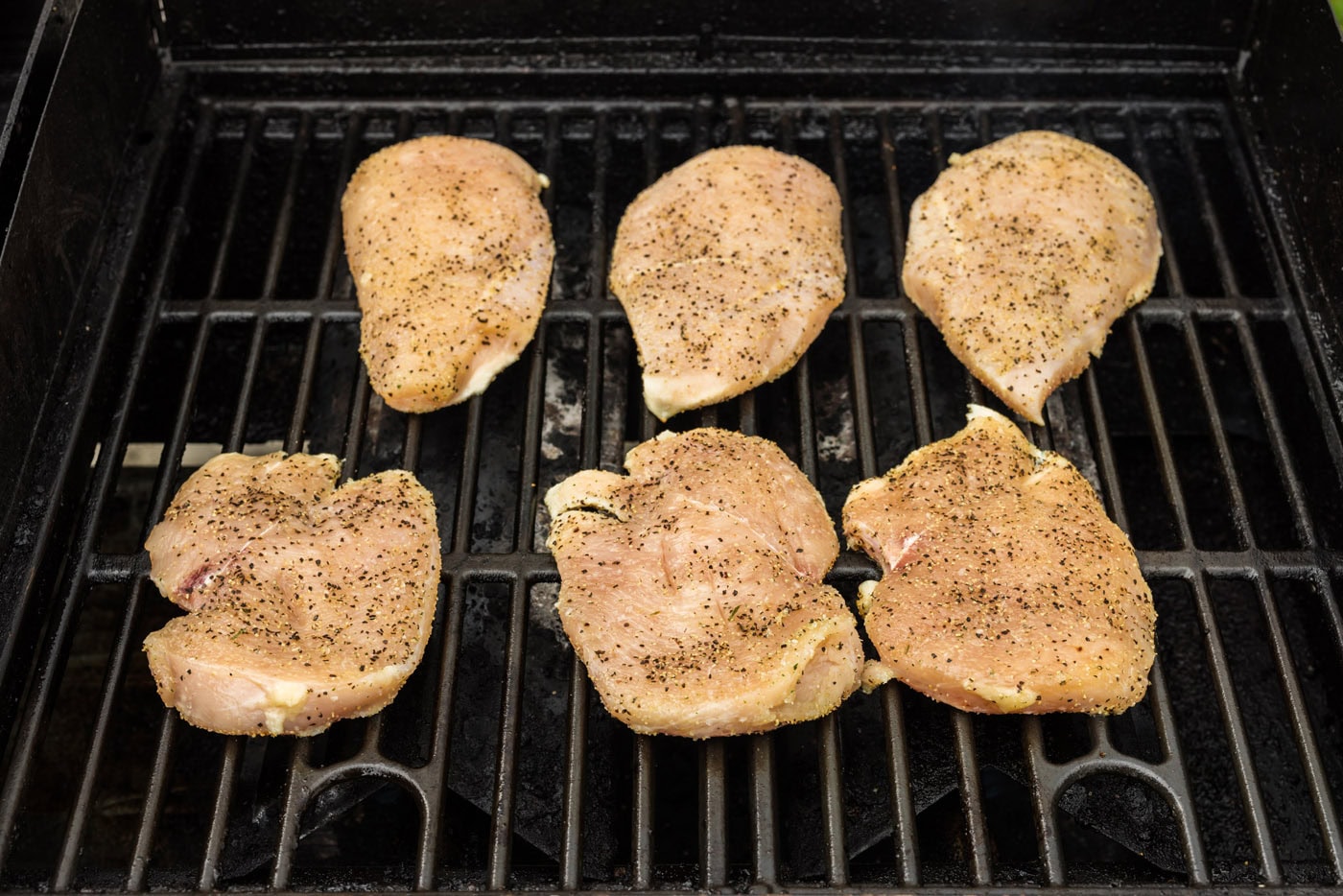 seasoned chicken breasts cooking on the grill