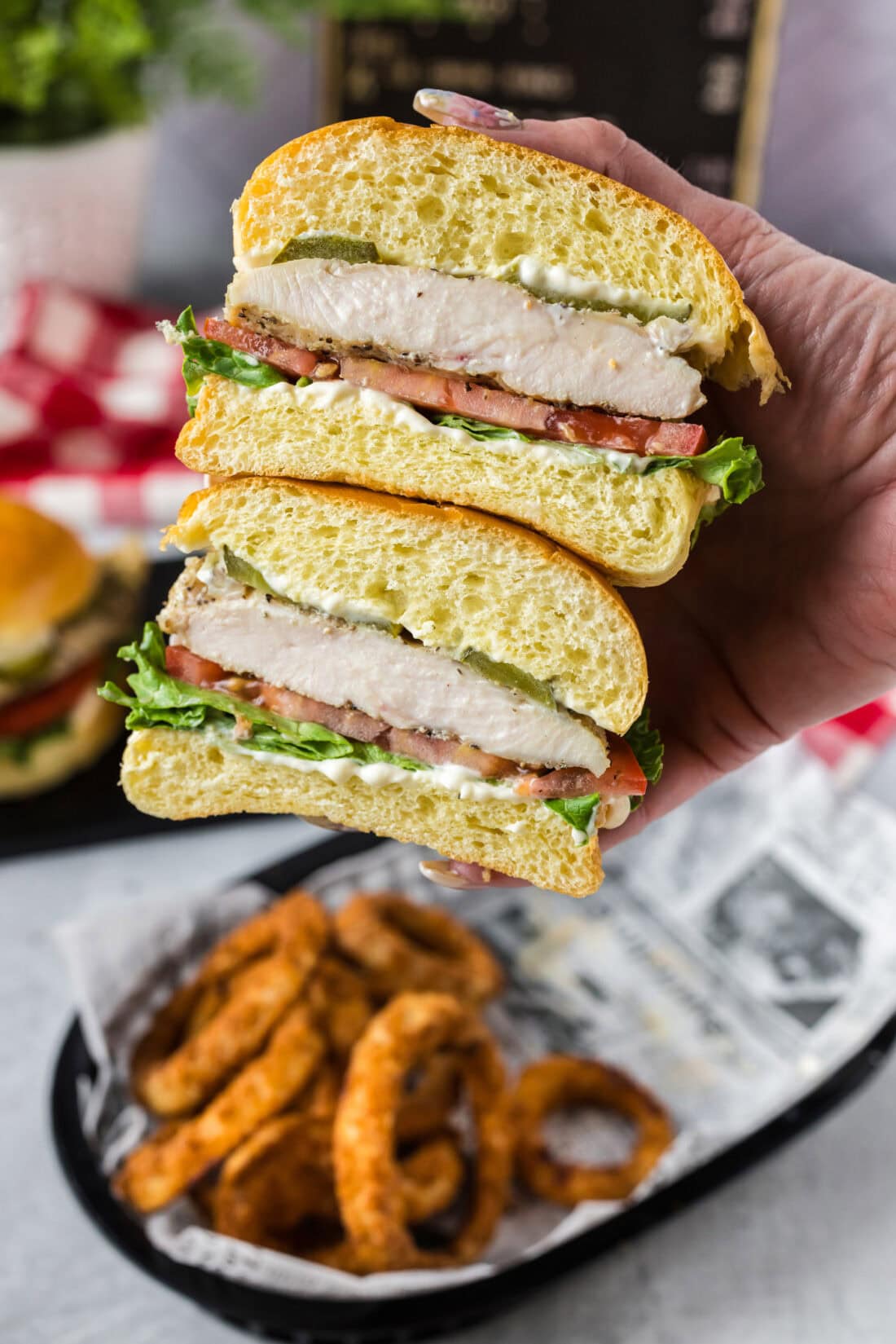 Hand holding a Chicken Sandwich that has been cut in half