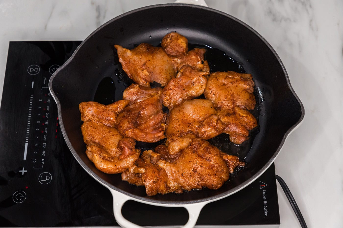 cooking marinated chicken in a pan