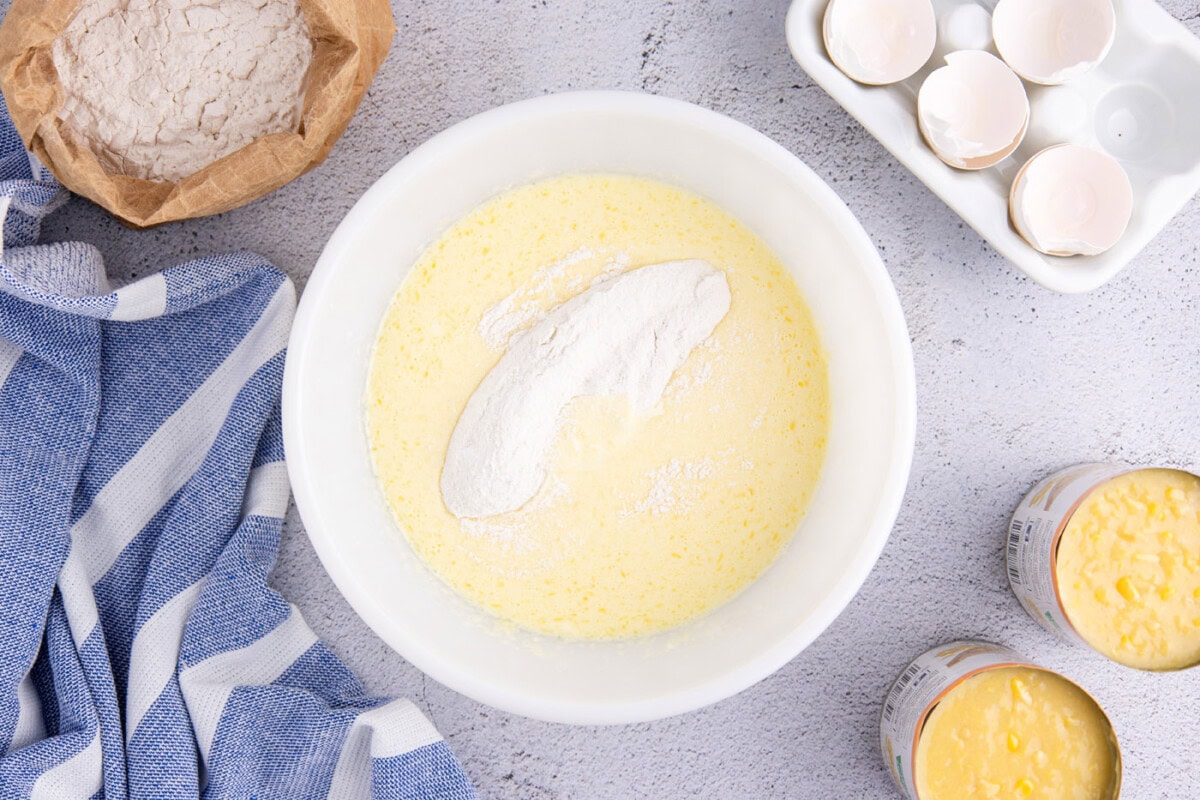 adding dry ingredients to wet ingredients in a mixing bowl