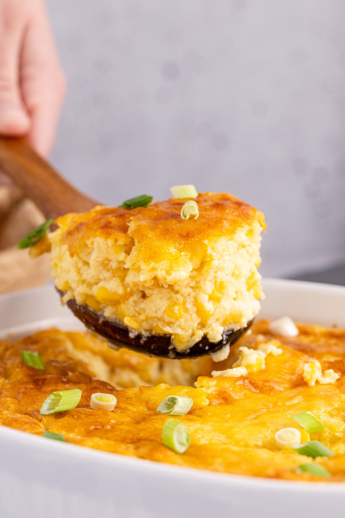 Scoop of Corn Pudding being lifted out of the baking dish