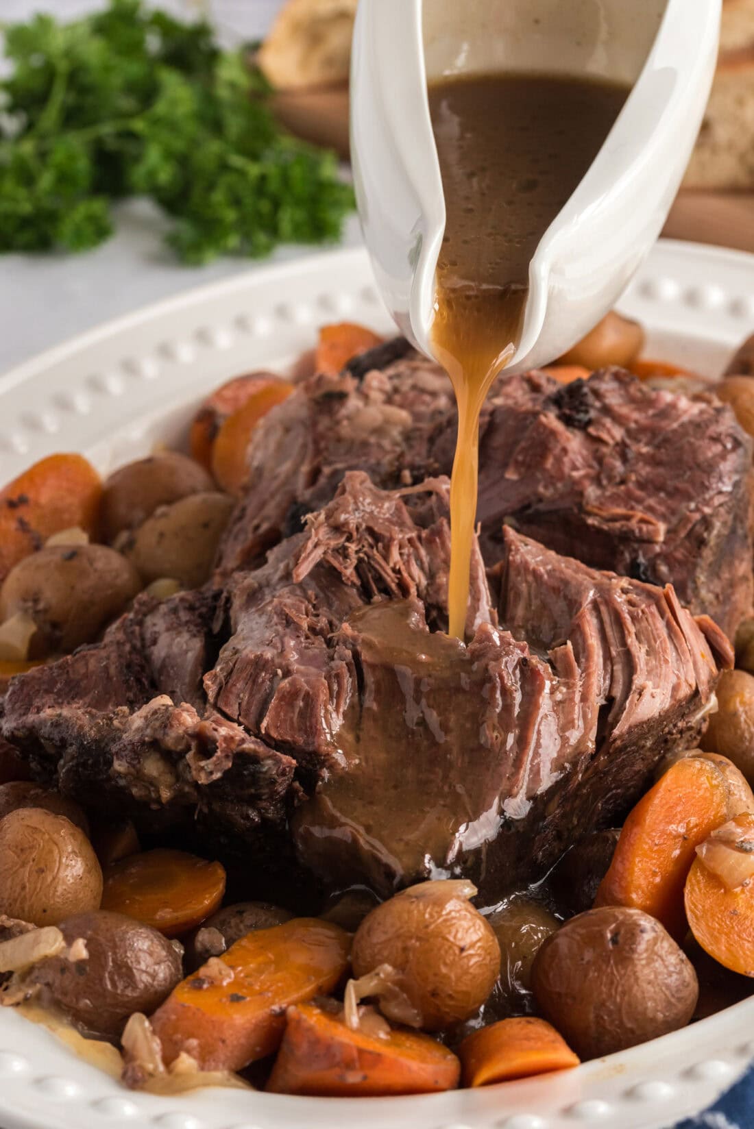 Gravy being poured over Crockpot Roast Beef on a platter