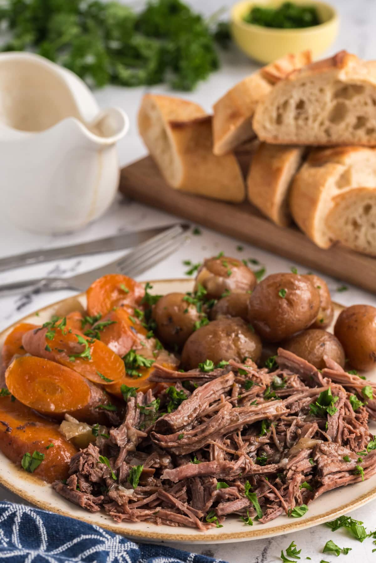 Shredded Crockpot Roast Beef on a platter with potatoes and carrots