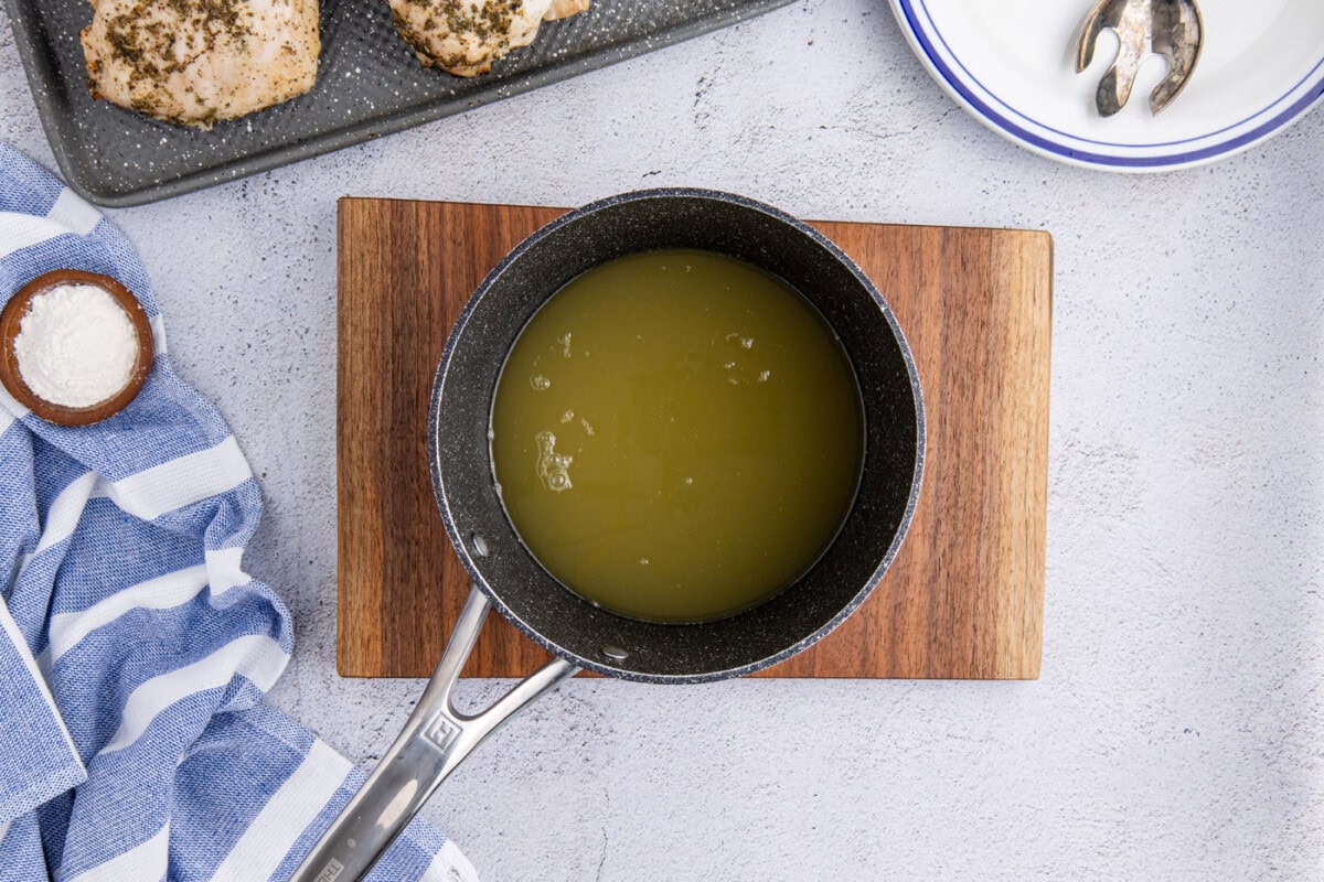 apple cider and chicken stock in a saucepan