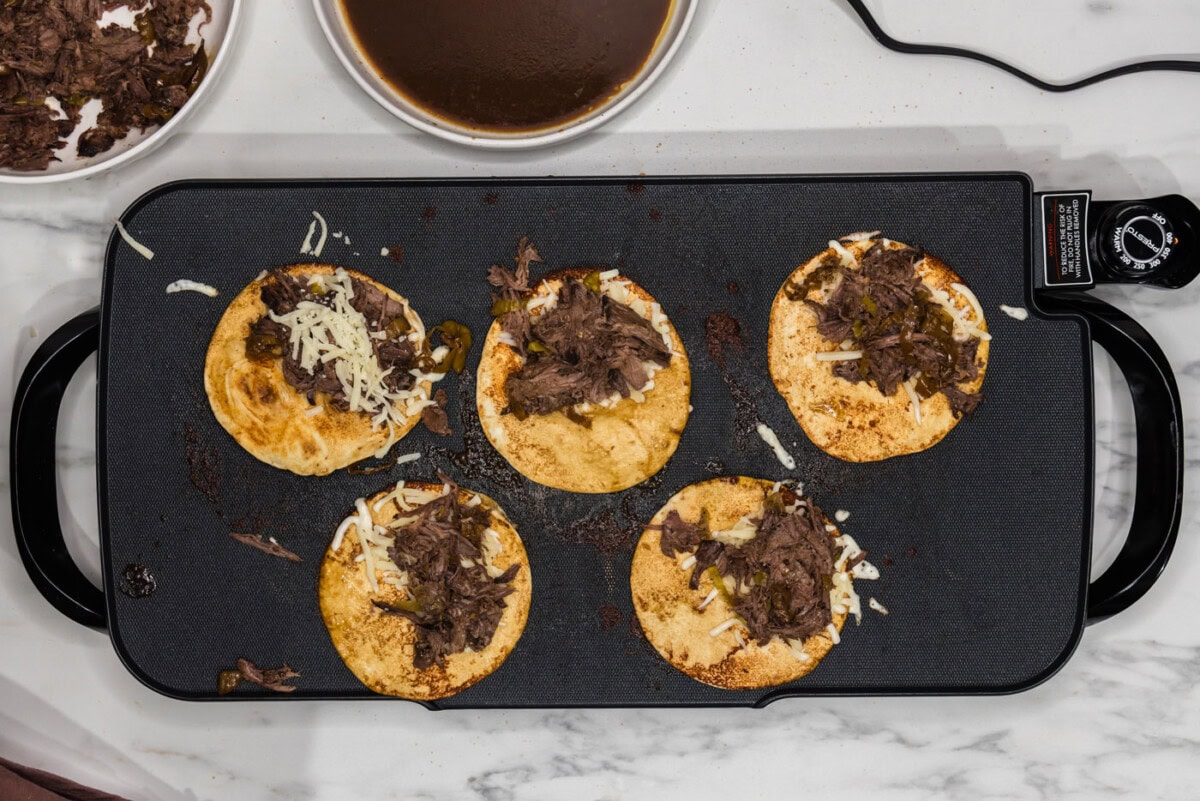 shredded pot roast on top of cheese and au jus soaked tortillas
