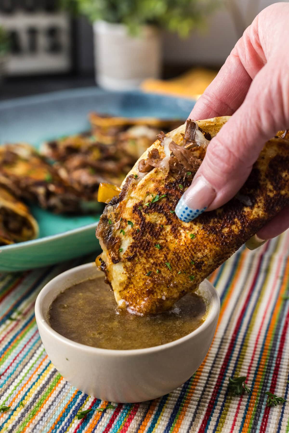 Mississippi Pot Roast Taco being dipped in a bowl of roast juices