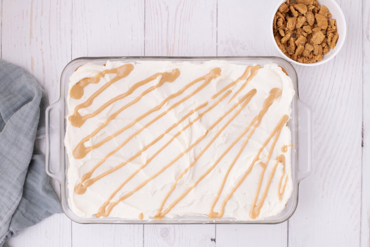 peanut butter drizzle over no bake nutter butter icebox cake in a pan