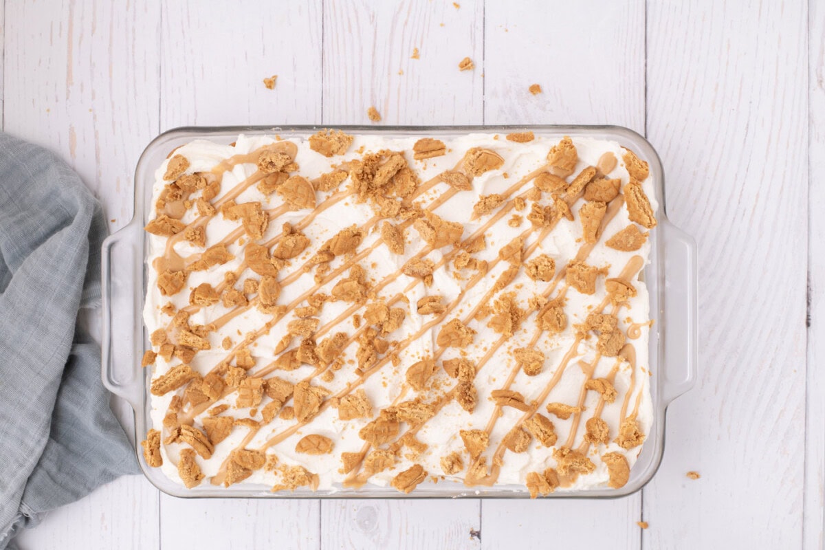 Nutter butter icebox cake in a dish with crushed cookies and peanut butter drizzle on top