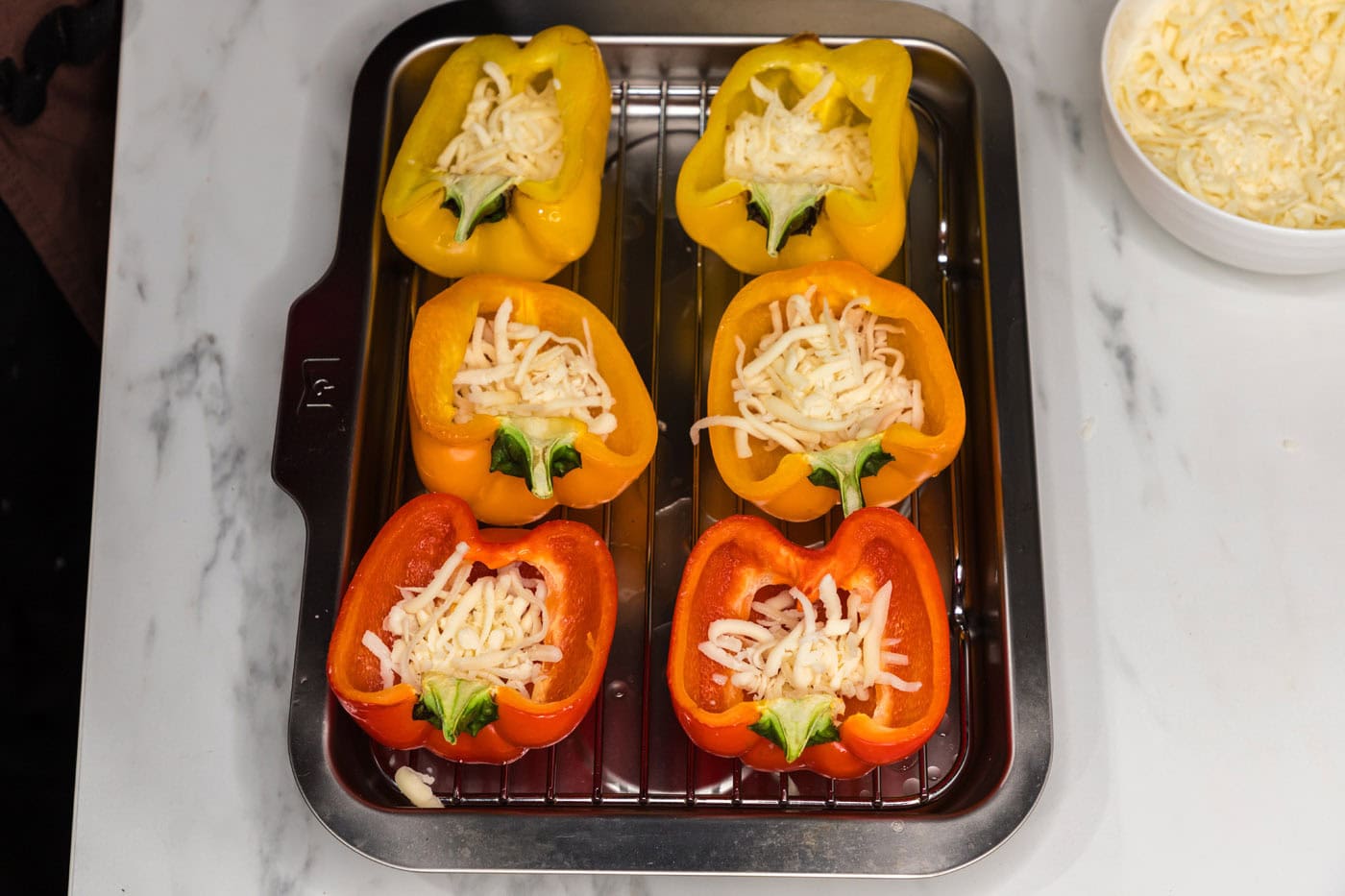 halved bell peppers on a baking sheet with cheese
