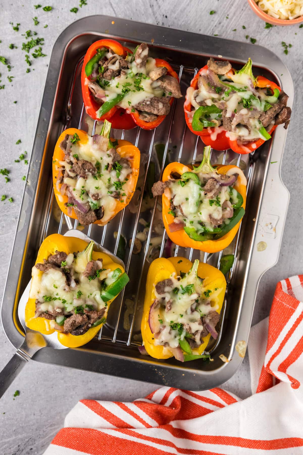 Spatula picking up a Philly Cheesesteak Stuffed Pepper off a pan of Philly Cheesesteak Stuffed Peppers