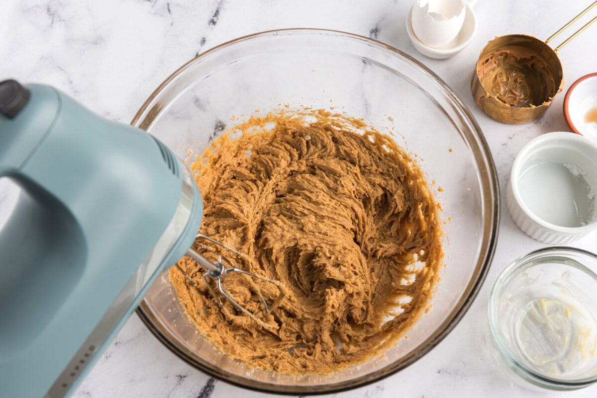 beating egg into peanut butter cookie dough in a bowl