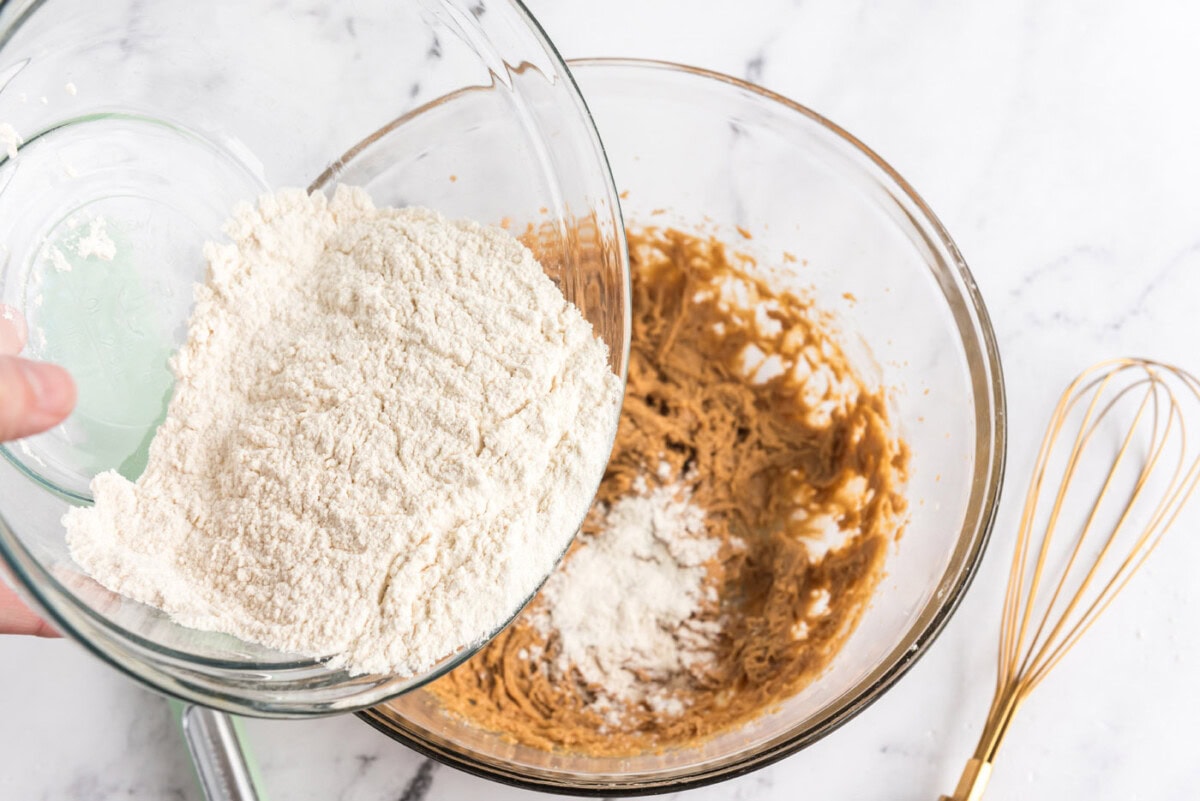 adding dry ingredients to wet ingredients for peanut butter cookie dough