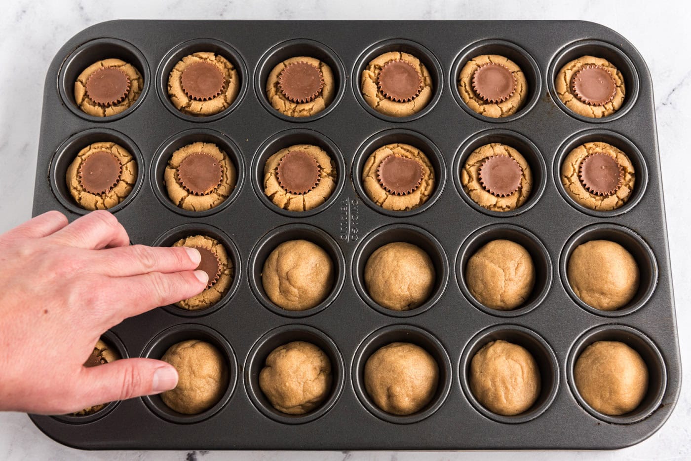 pressing Reeses mini peanut butter cups into peanut butter cookies in a mini muffin pan