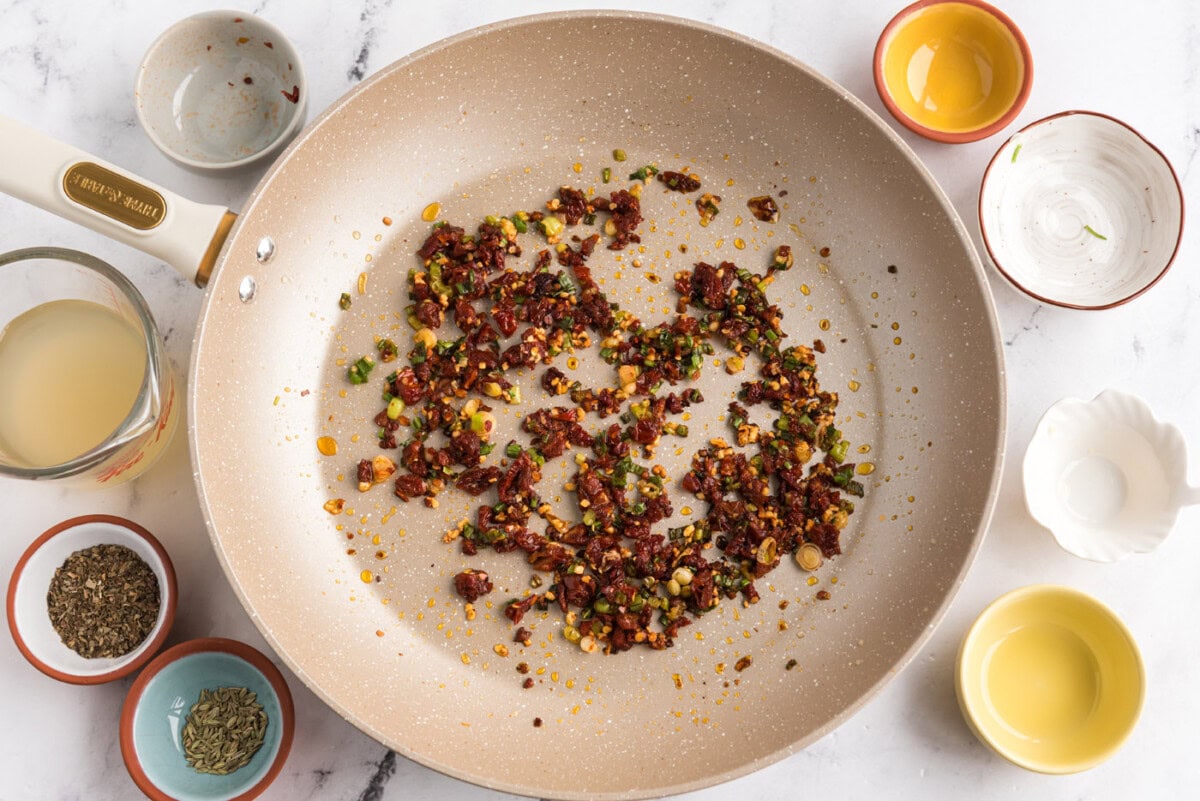 red pepper flakes and sun dried tomatoes added to skillet with garlic and green onions