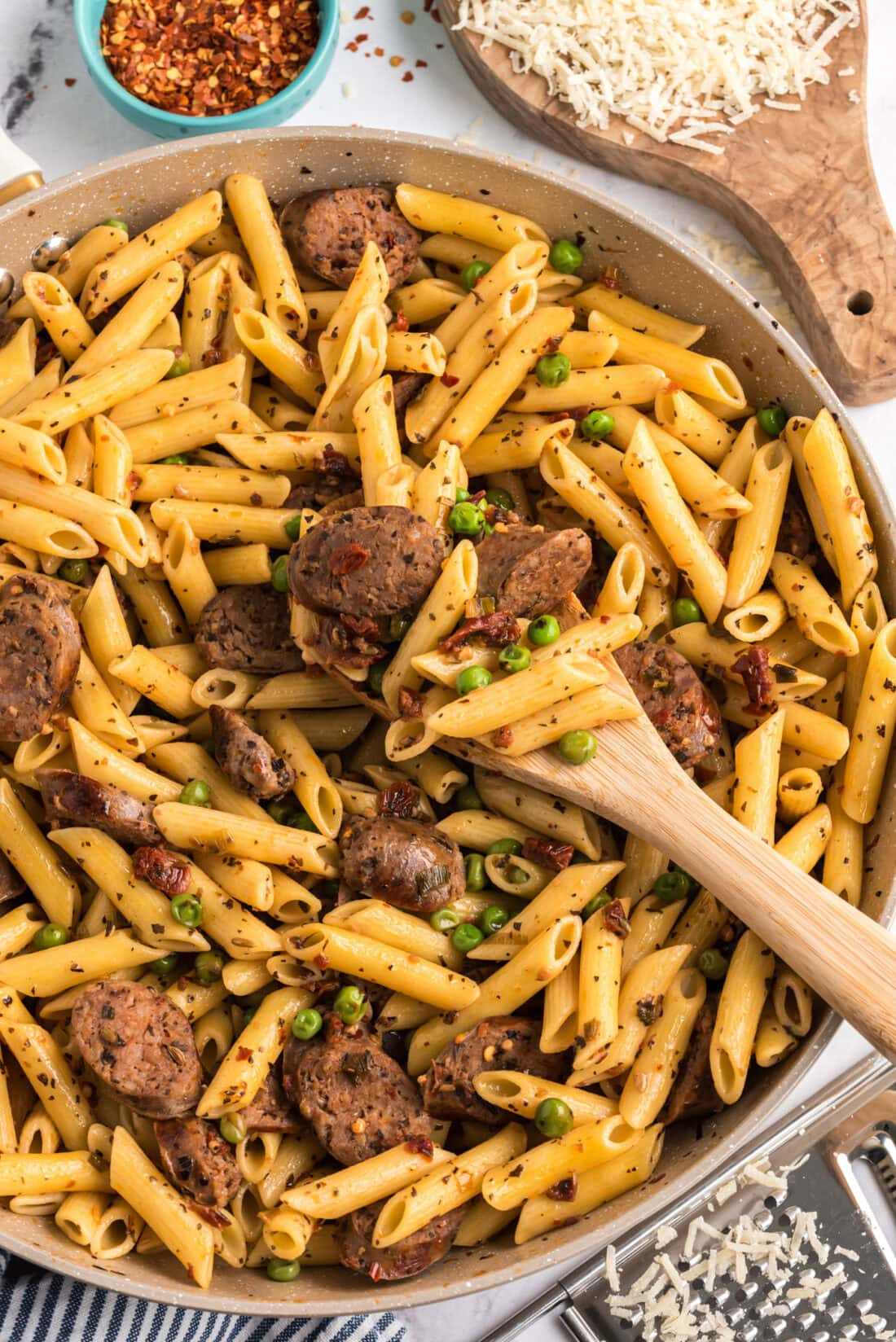 Sausage, Penne & Peas in a skillet with a spoon