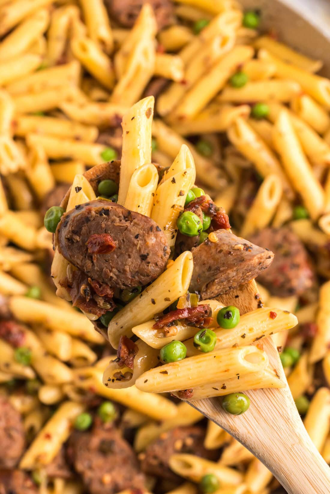 Close up photo of a spoonful of Sausage, Penne & Peas
