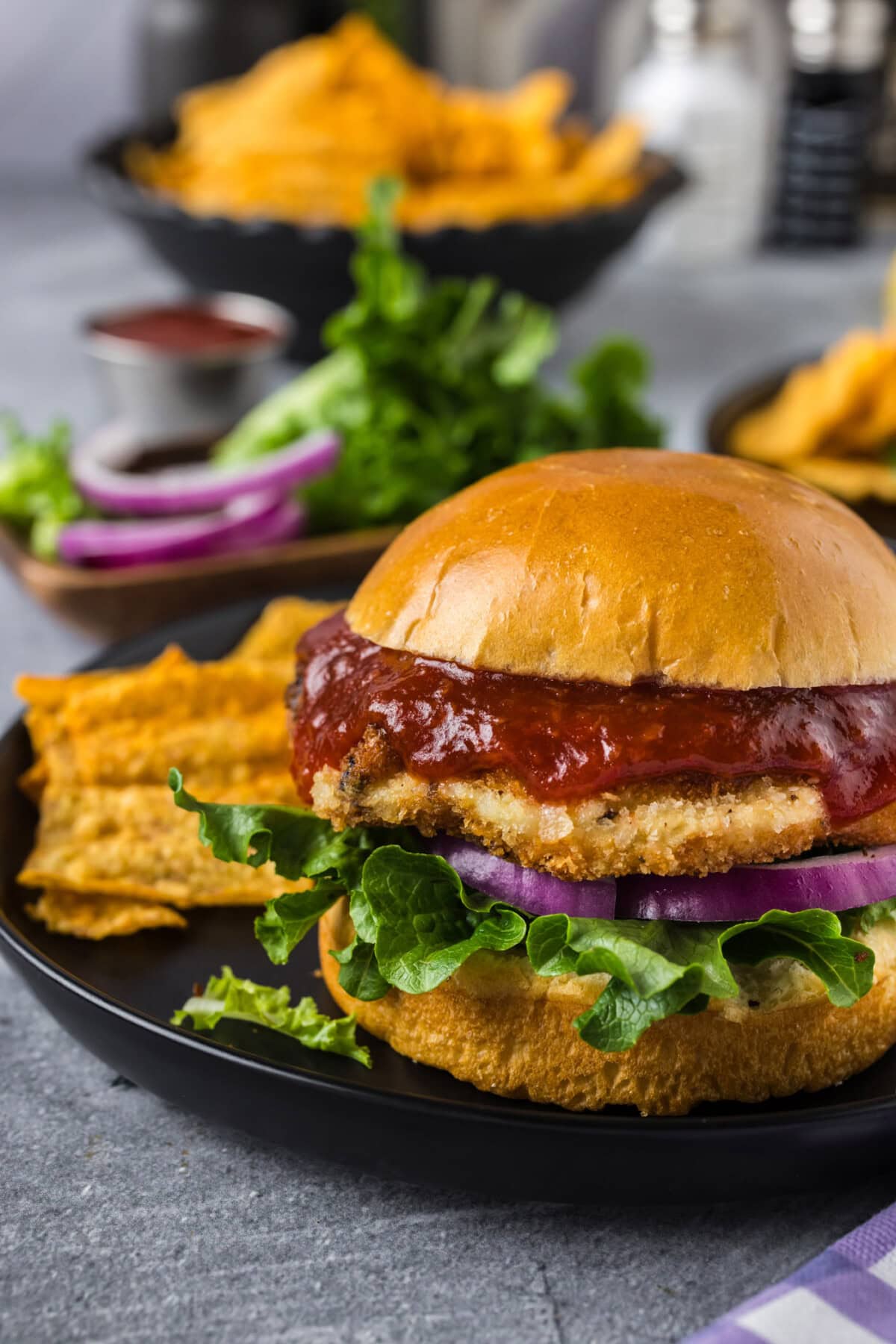 Close up photo of a Shrimp Burger on a plate with chips on the side