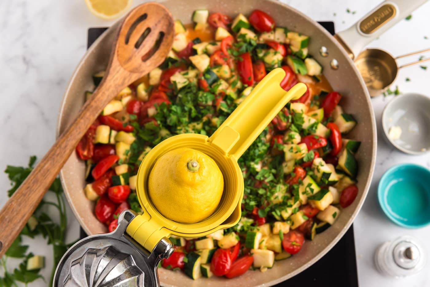 adding lemon juice to pan of zucchini and tomatoes with parsley