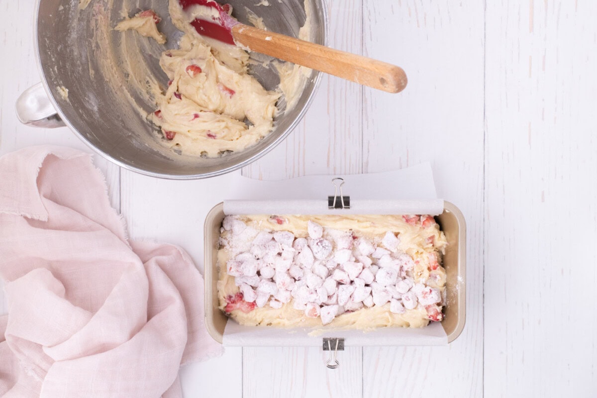 strawberry pound cake batter in a loaf pan topped with strawberries
