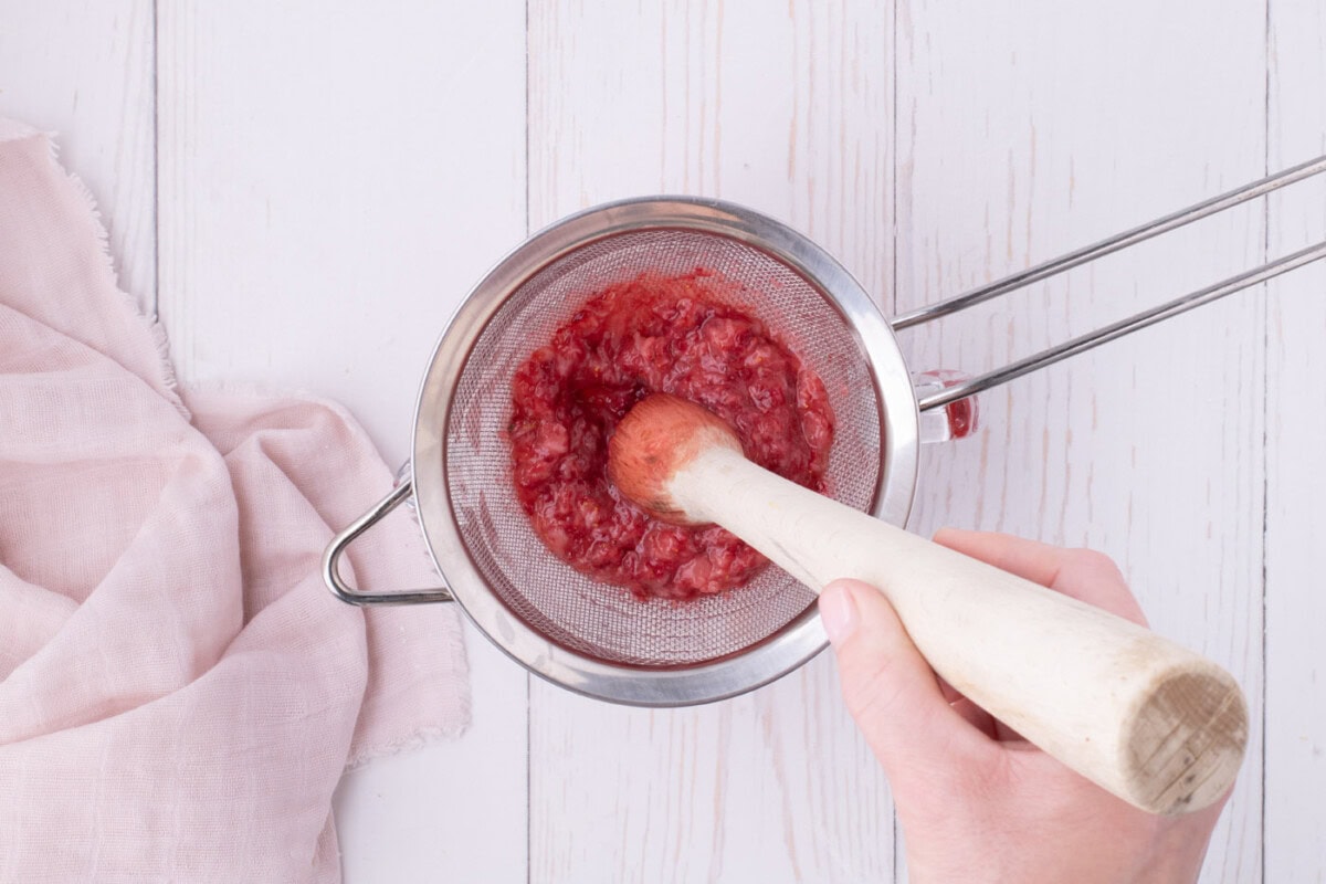 muddling strawberries through a fine mesh sieve