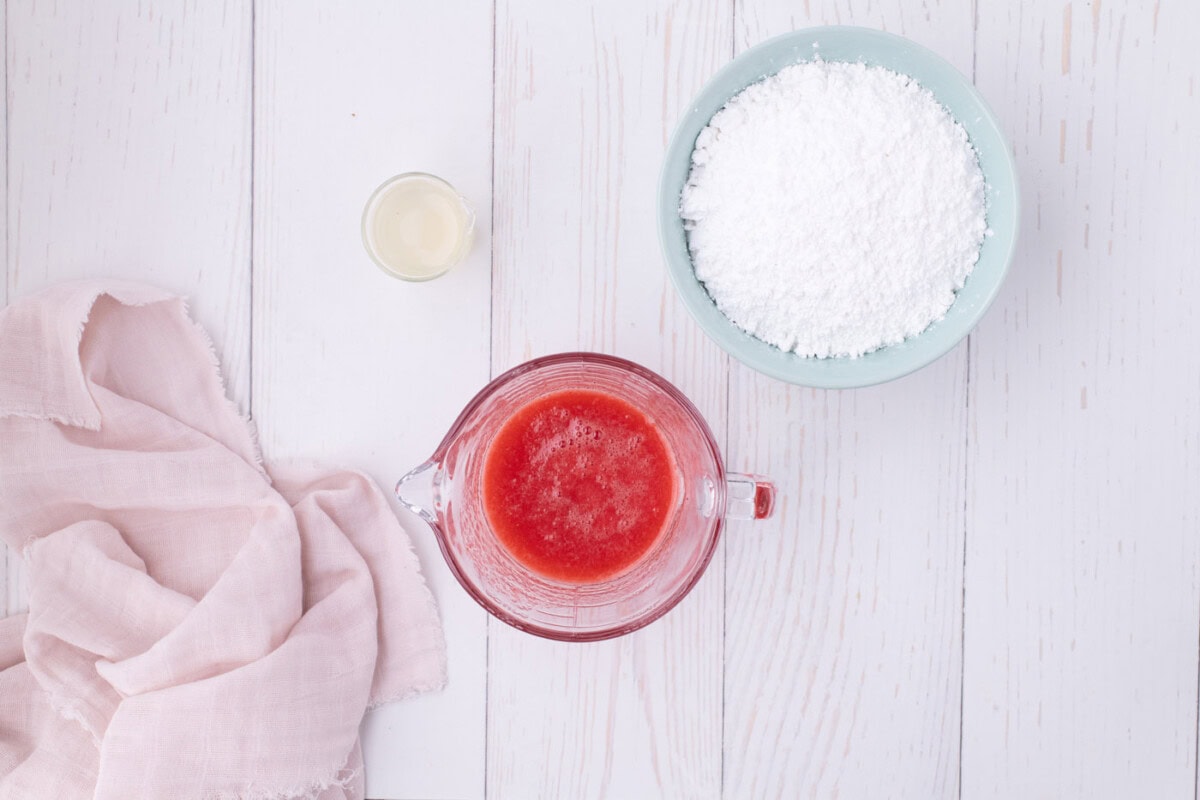 strawberry juice in a measuring cup next to powdered sugar