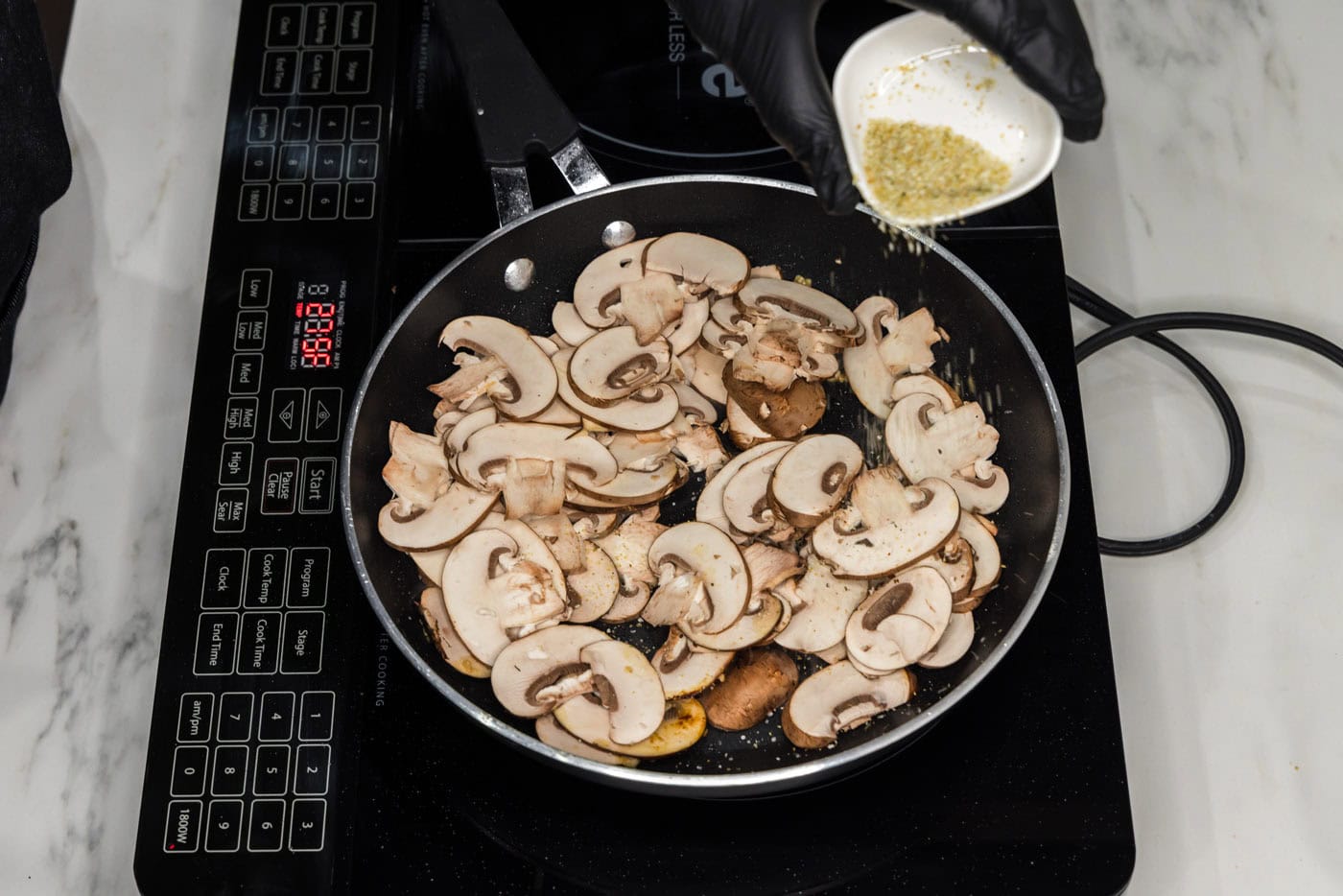 sliced mushrooms cooking in a skillet with oil