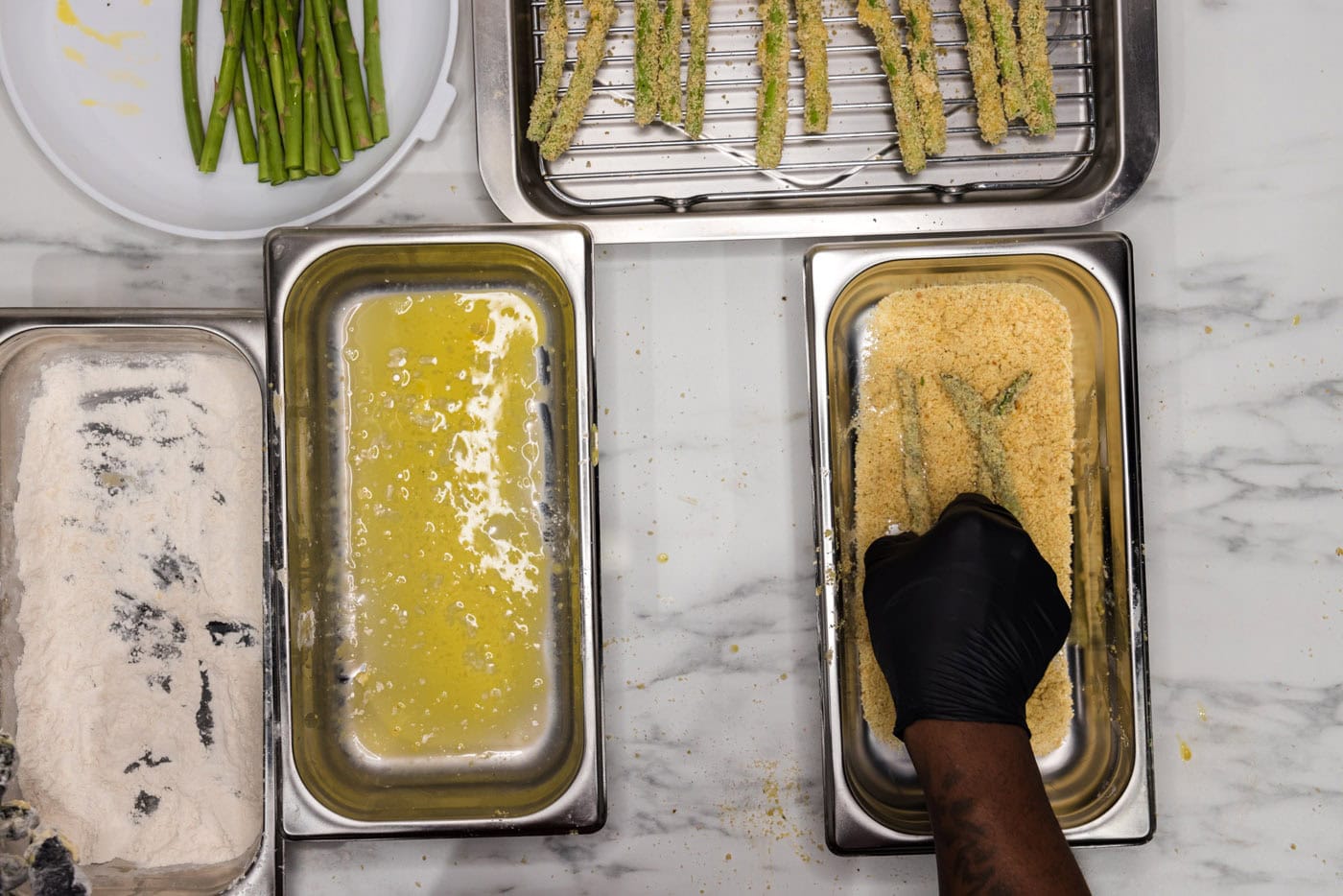 dredging asparagus spears in breadcrumb mixture