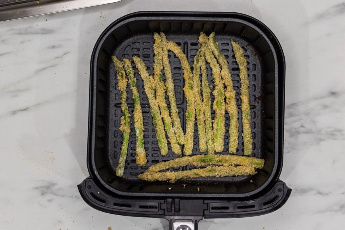 breaded asparagus fries in an air fryer basket