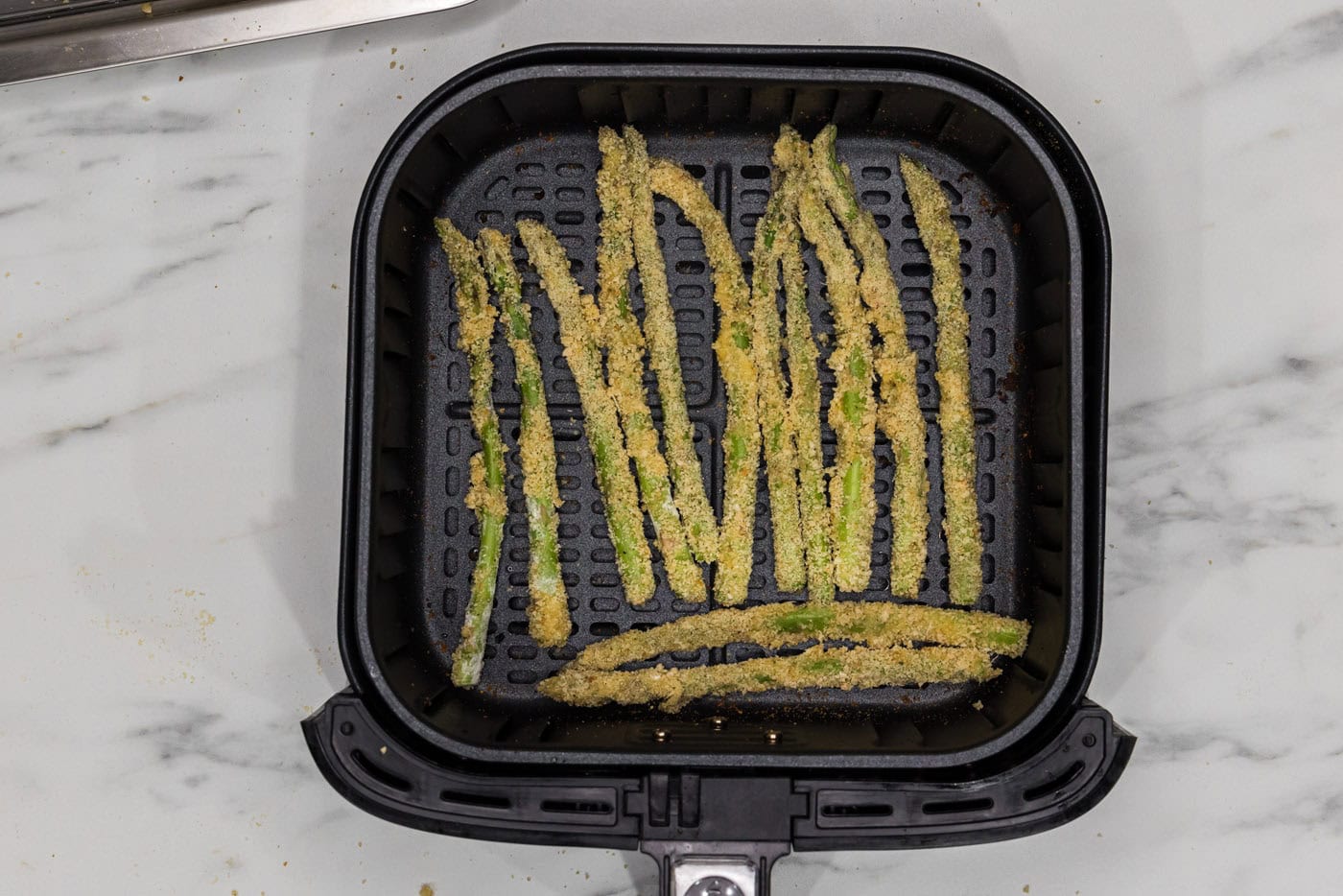 breaded asparagus fries in an air fryer basket