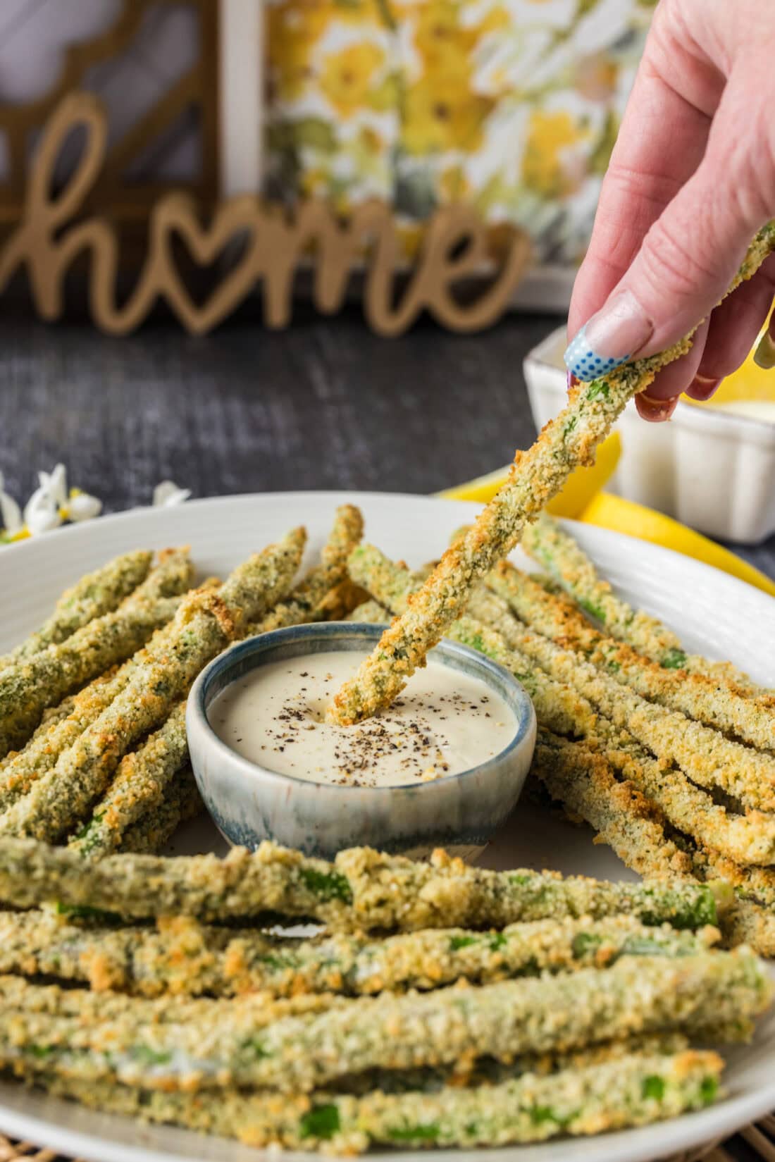 An Air Fryer Fried Asparagus spear being dipped into a bowl of ranch