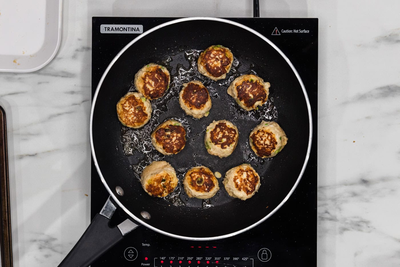 pan searing chicken meatballs in a skillet