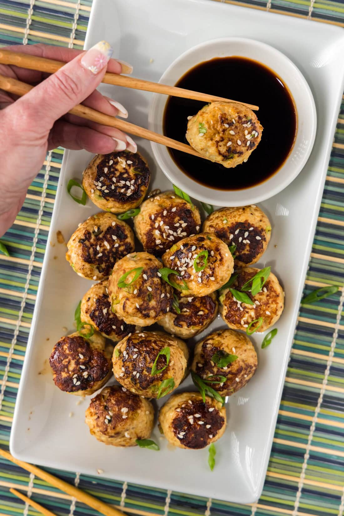 Asian Meatball being dipped into a bowl of soy sauce 