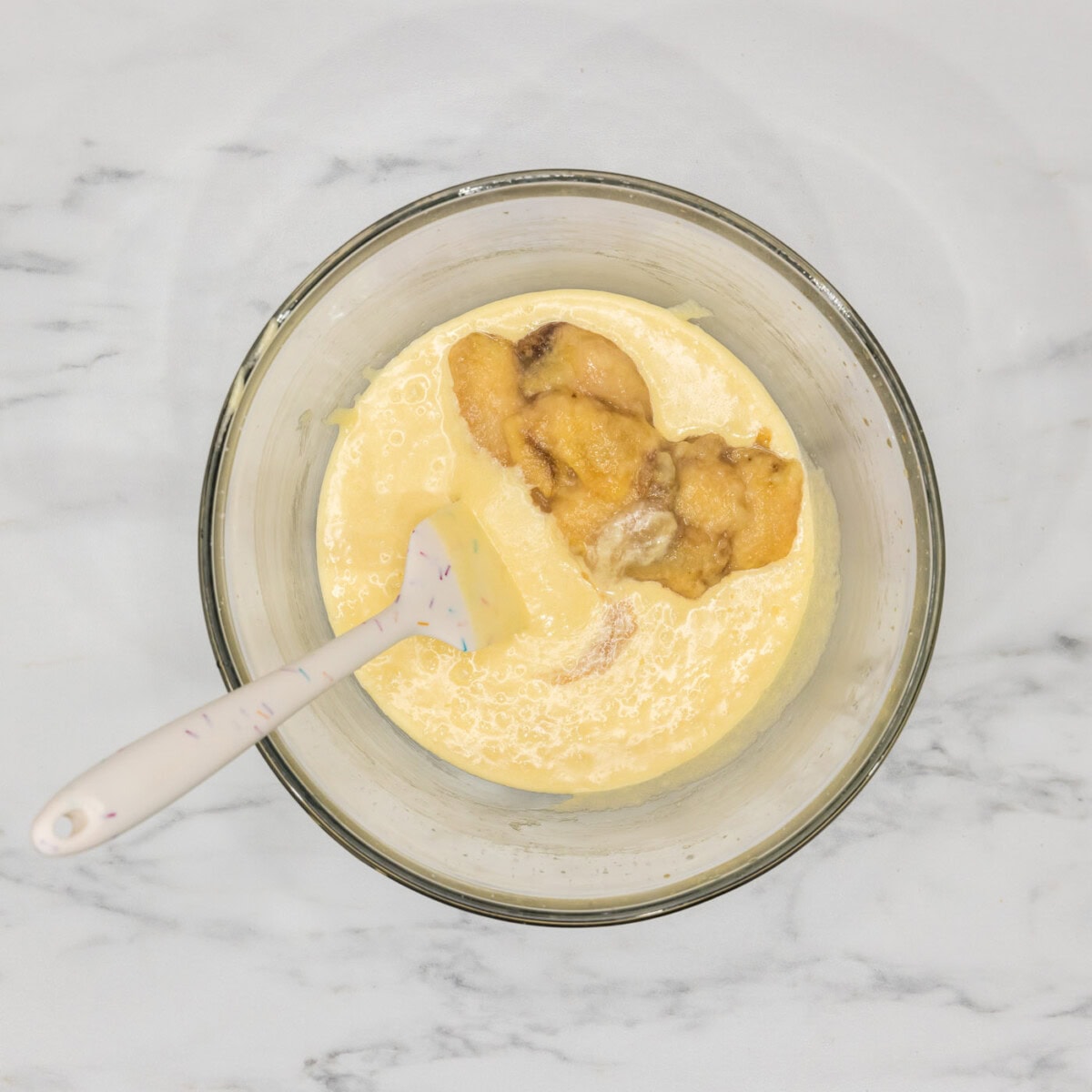mashed bananas added to bundt cake batter in a bowl