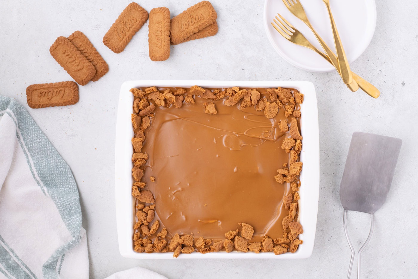 Biscoff icebox cake in a baking dish with cookie butter and crushed cookies as garnish