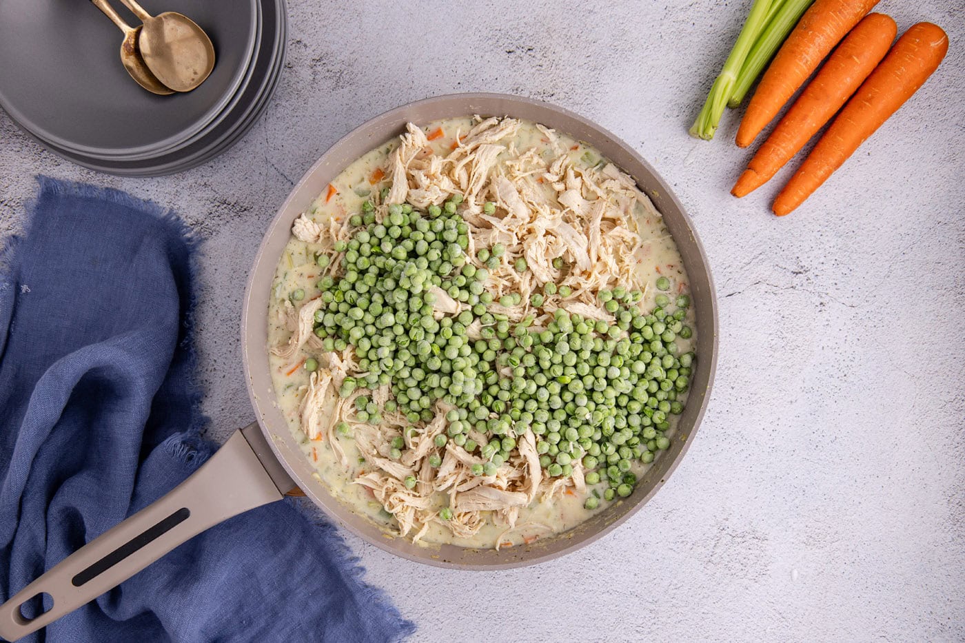 frozen peas added to chicken pot pie mixture in a skillet