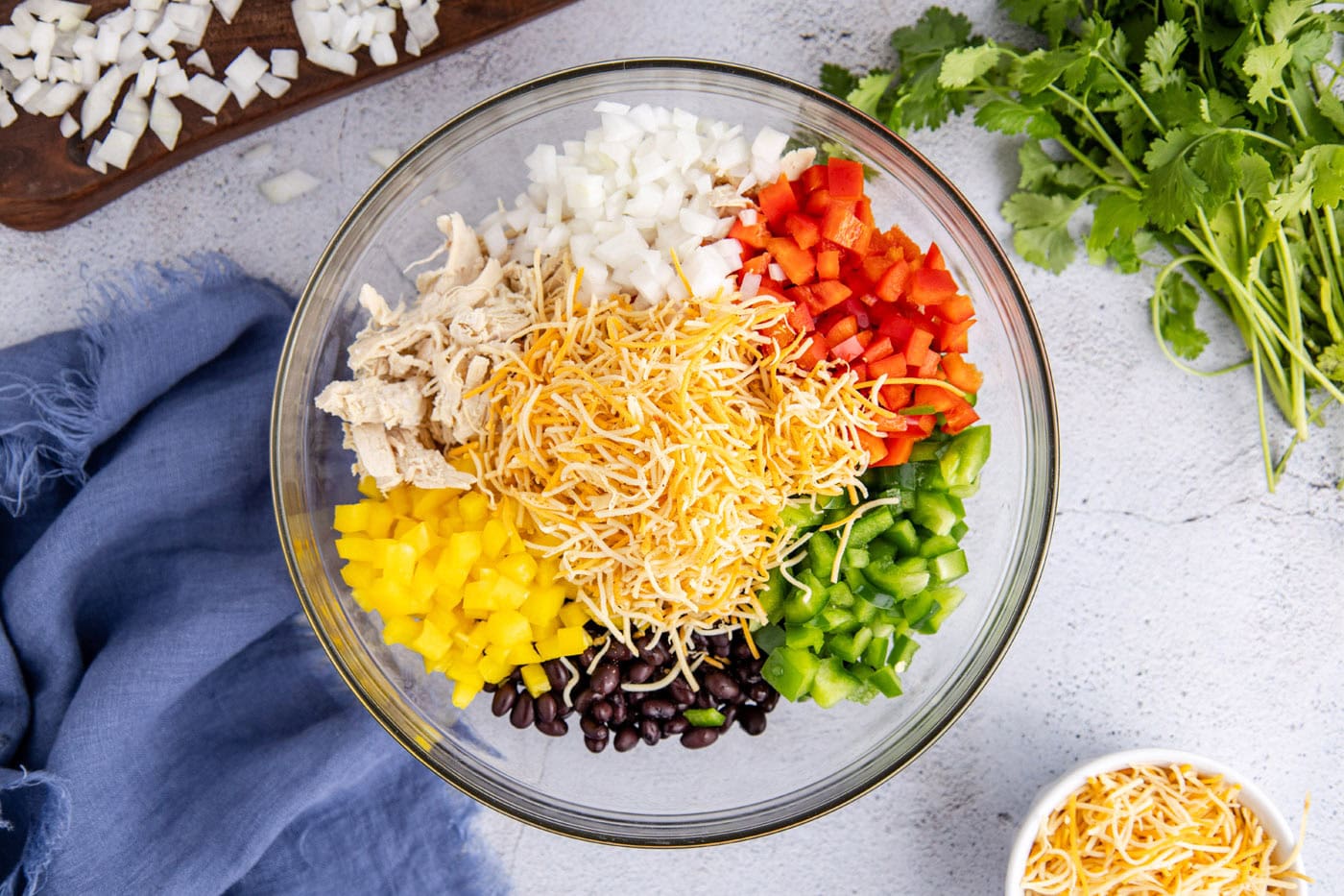 shredded cheese, diced bell peppers, onion, chicken, and black beans in a bowl