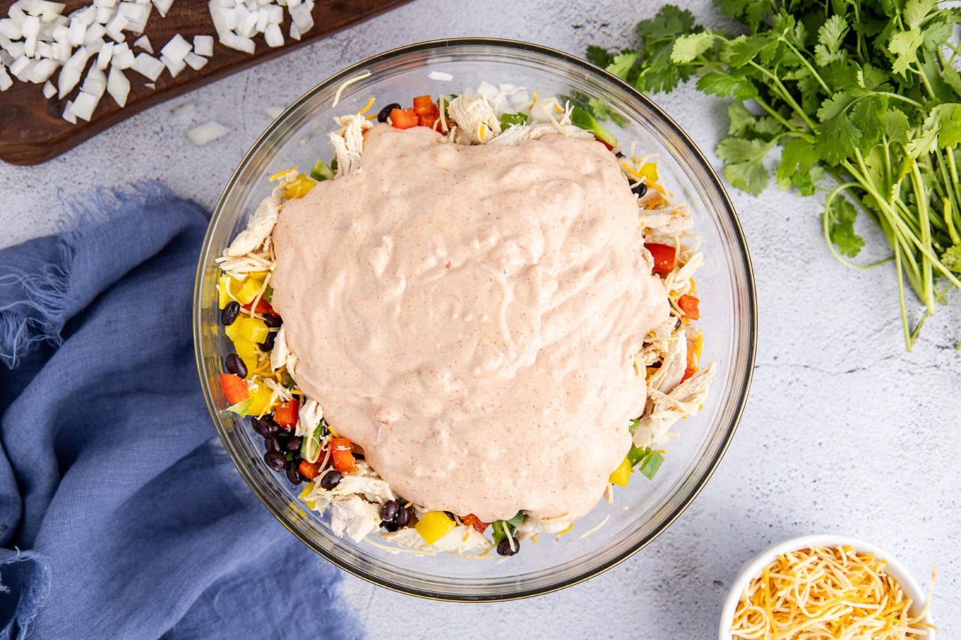 sour cream mixture on top of chicken taco casserole ingredients in a bowl