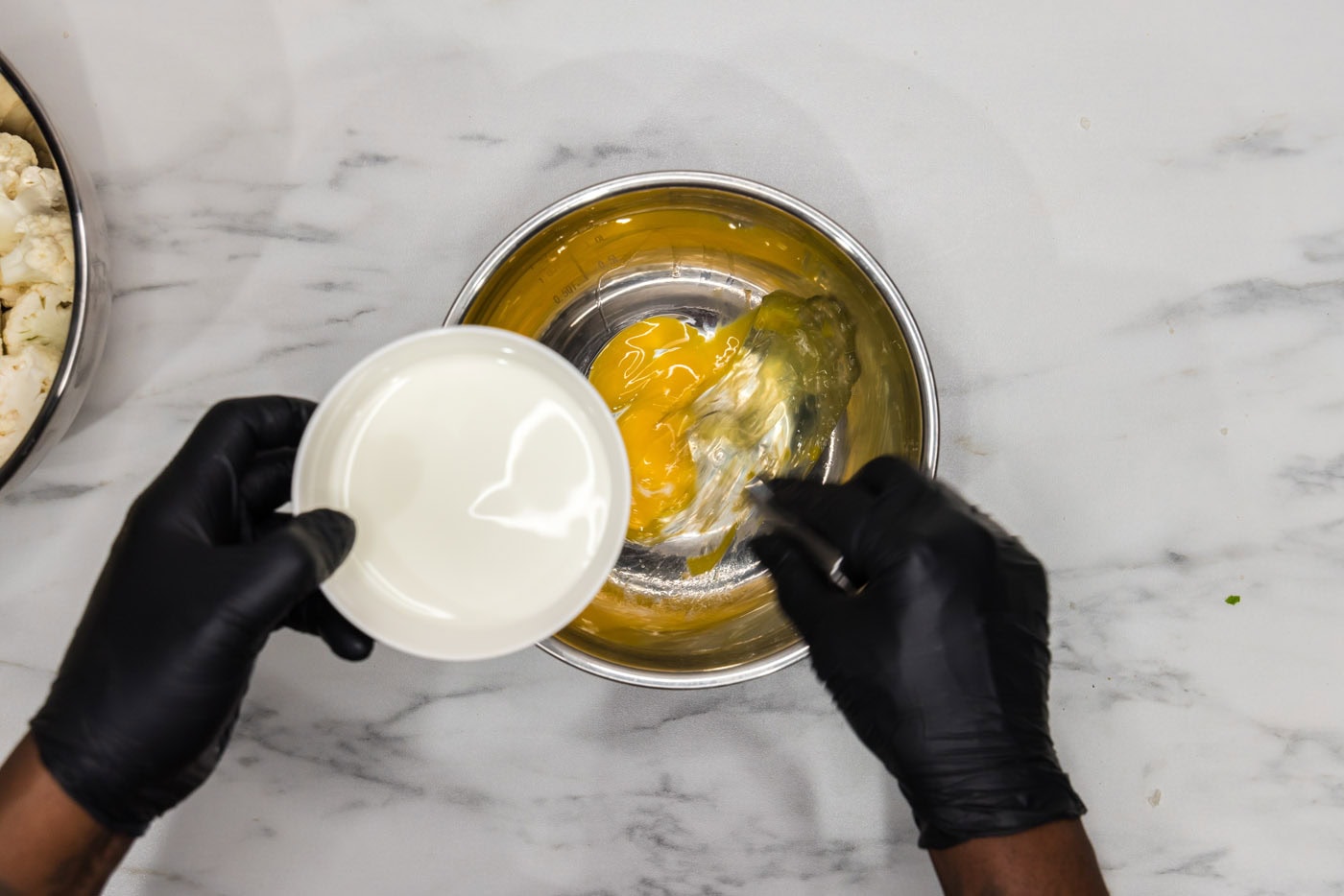 adding milk to whisked eggs in a bowl