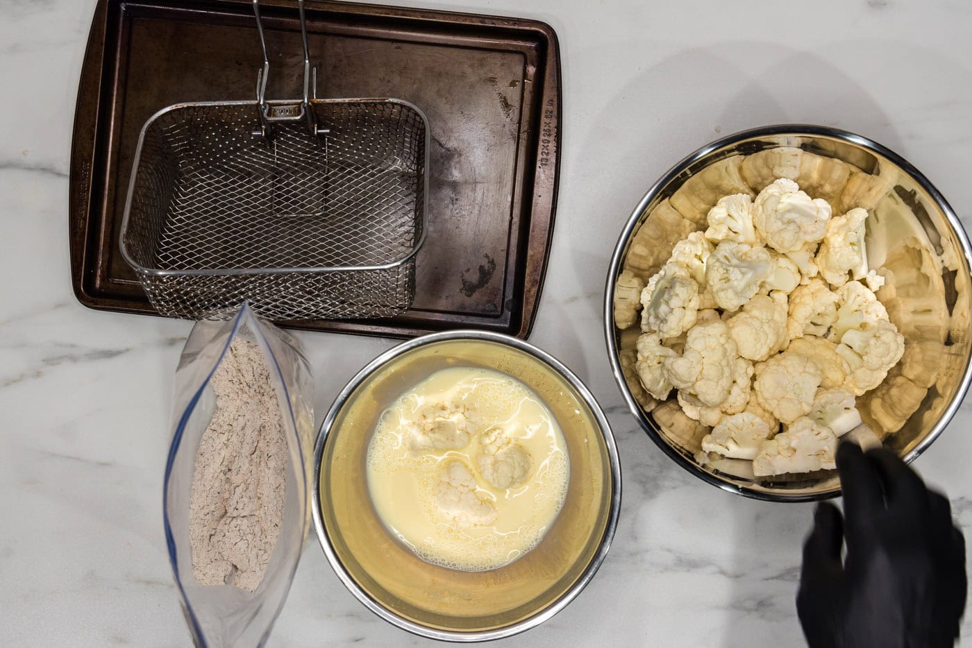 breaded cauliflower florets in a bowl of whisked eggs and milk