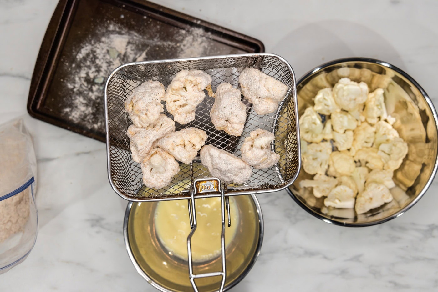 breaded cauliflower florets in a deep fryer basket