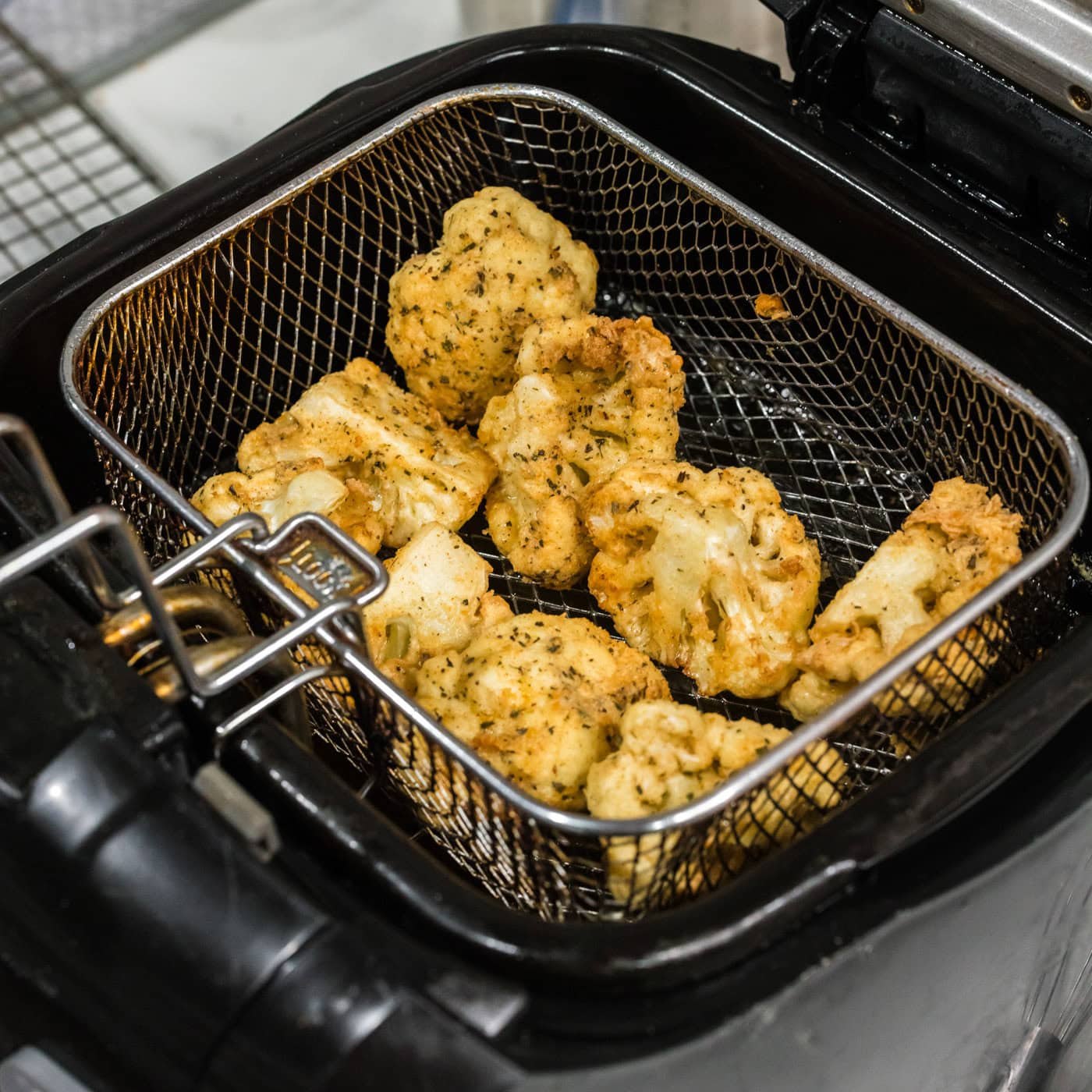 deep fried cauliflower florets in a fryer basket