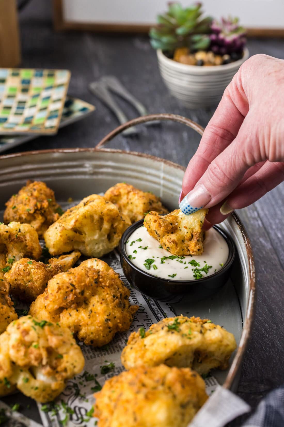 Hand dipping a Cauliflower floret into a bowl of ranch