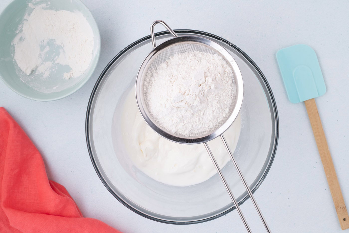 sifting self rising flour over melted vanilla ice cream in a bowl