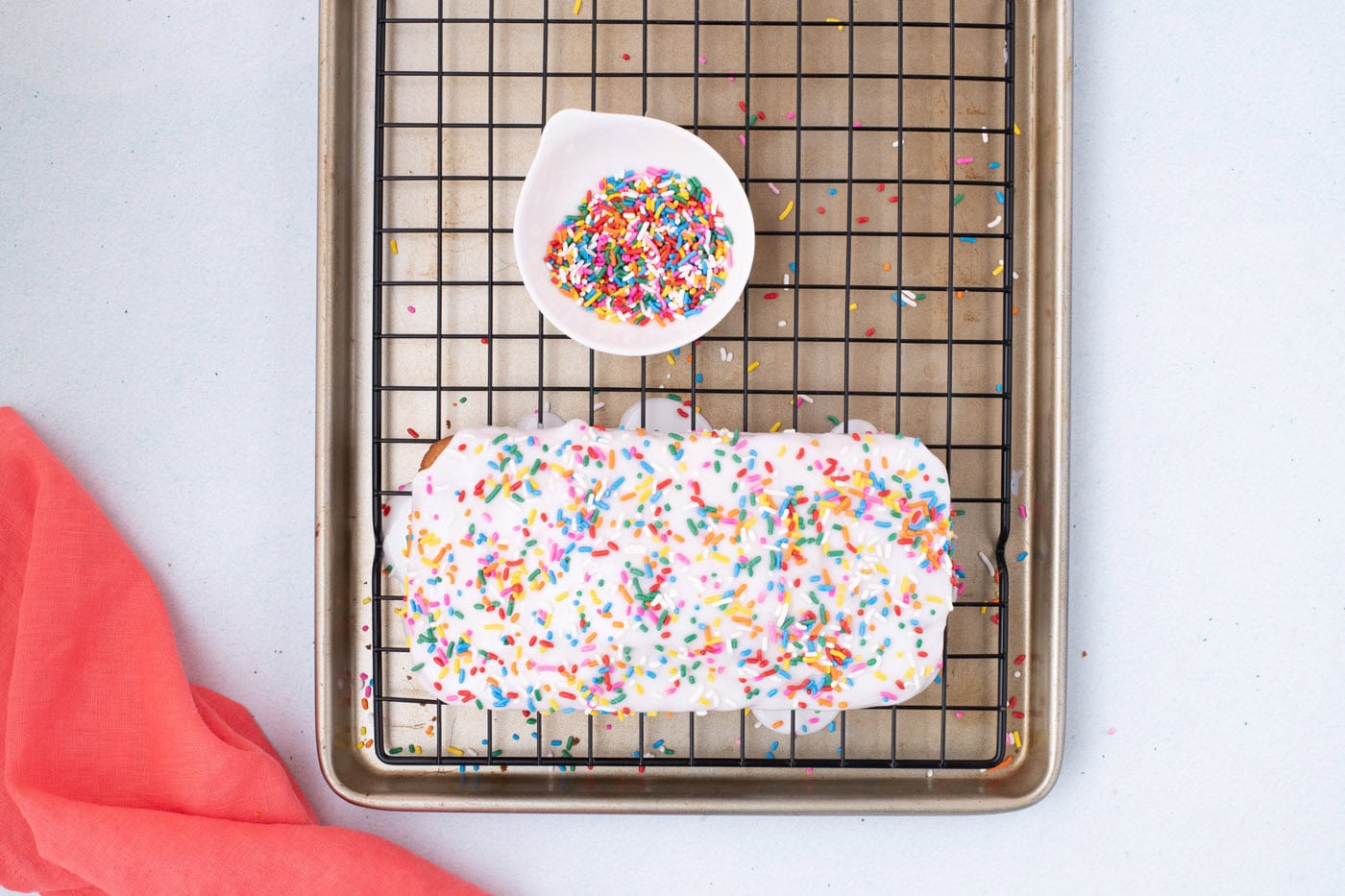 ice cream bread with glaze and sprinkles on a wire cooling rack