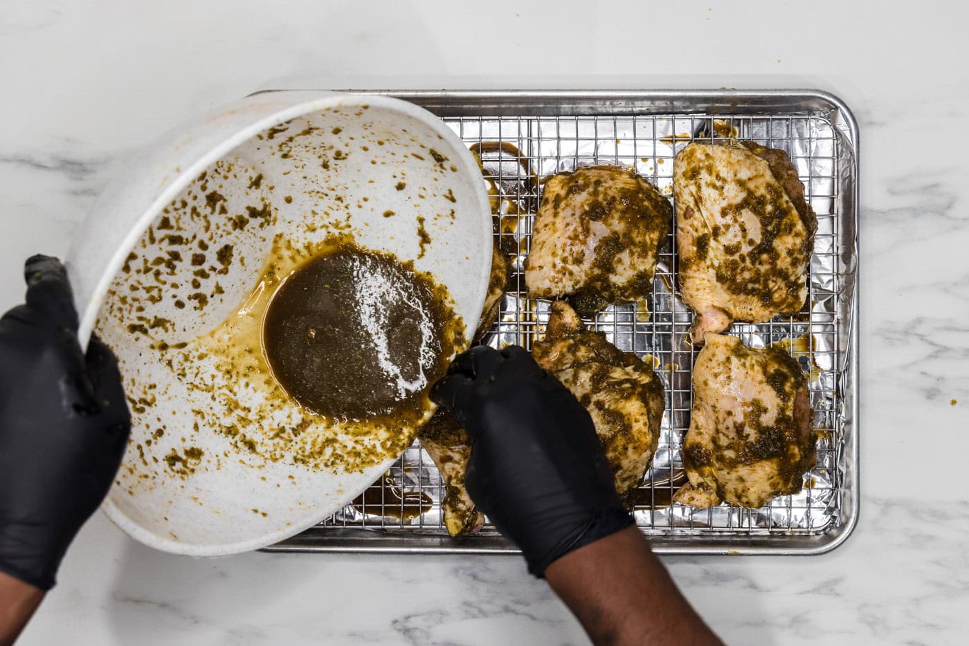 pouring extra marinade over chicken on a wire rack