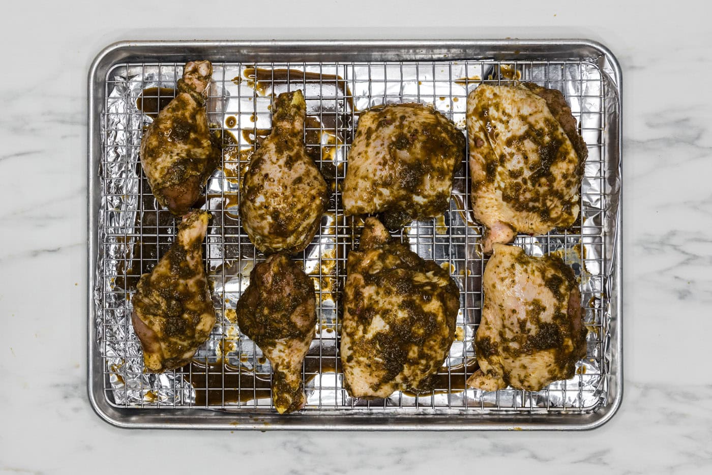 marinated jerk chicken on a wire rack over a baking sheet