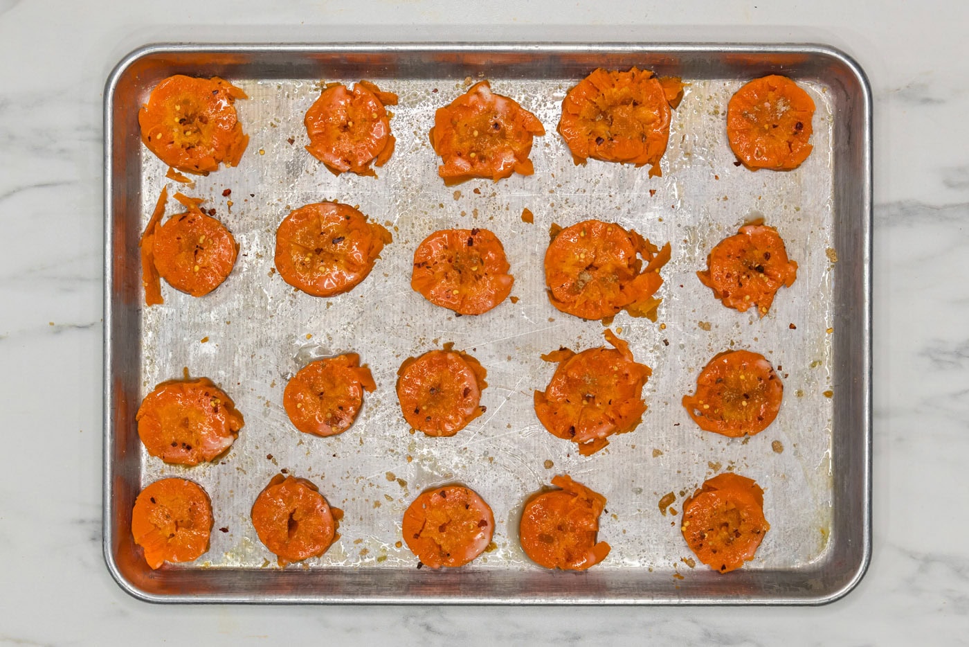 seasoned smashed carrots on a baking sheet