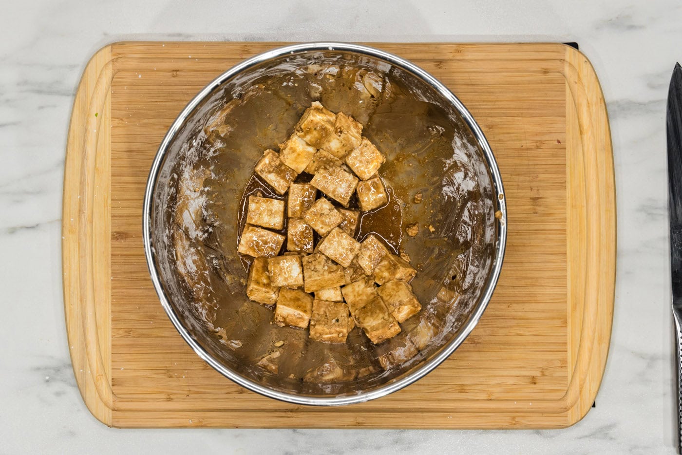 cubed tofu in a bowl with soy sauce, cornstarch, and sesame oil