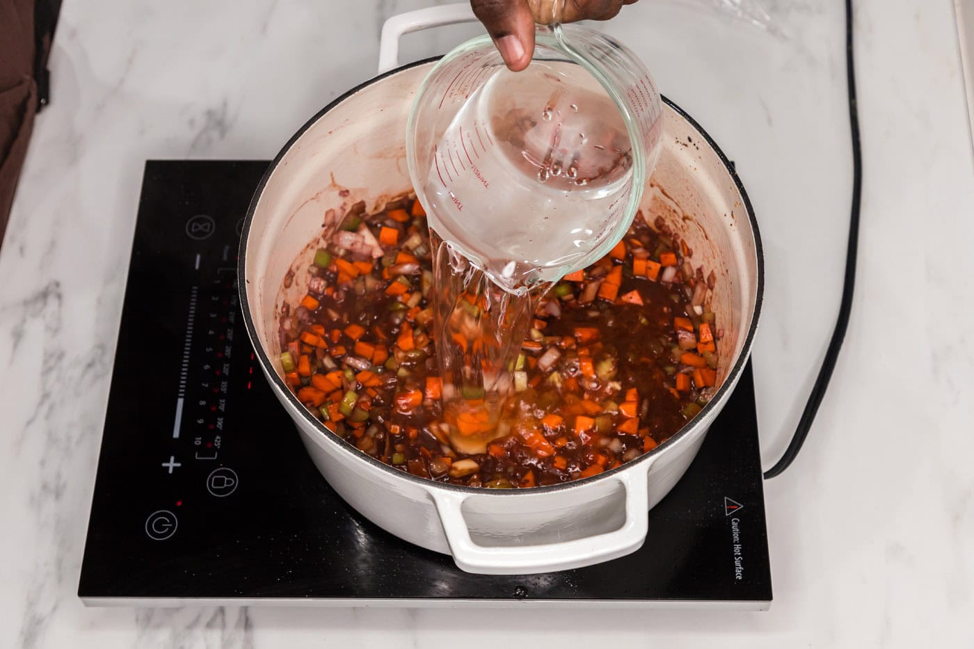 pouring water into braised oxtail aromatics