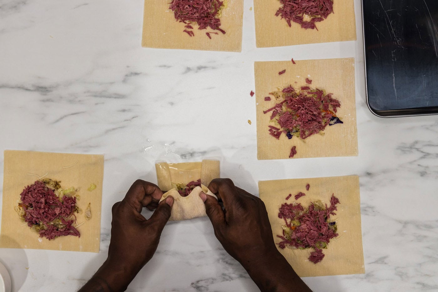 hands folding egg roll wrappers